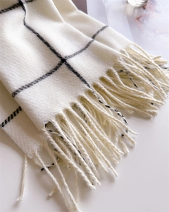 Detailed view of ivory and black plaid knit scarf with long decorative tassels