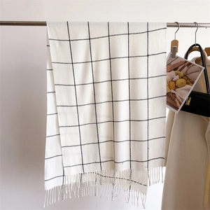 Detail of white and black plaid scarf with fringe, soft cashmere-like texture for winter