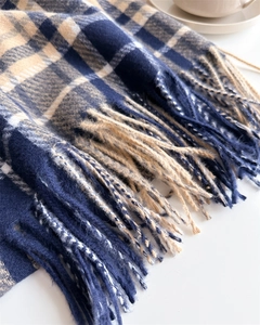 Close-up of classic blue and beige plaid scarf with soft fringe texture details