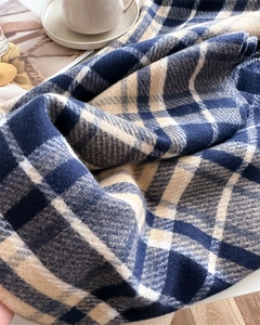 Close-up of soft plaid scarf texture with navy and khaki colors for winter style