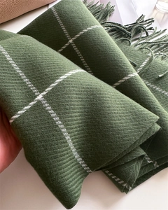 Macro shot of dark green plaid scarf showing twill weave texture and long fringe details