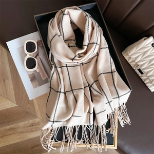Detail of soft beige plaid scarf with black stripes and decorative tassels on display
