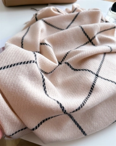 Close-up of soft plaid beige cashmere scarf with elegant black grid texture and tassels