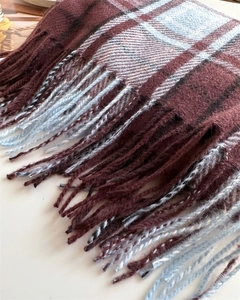 Detail shot of soft burgundy and blue plaid scarf with twisted tassel fringe edges