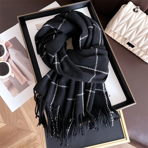 Detail of classic black and white plaid scarf with fringe on a stylish leather background