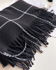 Close-up of black and white checkered scarf with soft cashmere-like texture and tassels