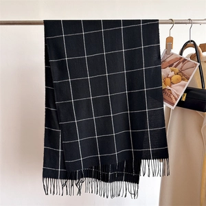 Close-up of black and white checkered scarf featuring soft fringe tassels and classic pattern