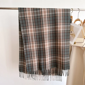 Close-up of classic grey, green and beige plaid pattern with fringe on soft scarf