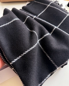 Close-up of classic black windowpane plaid scarf with soft twill texture and fringed detail