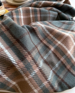 Close-up of thick plaid cashmere-like scarf showing soft woven texture and fringe details