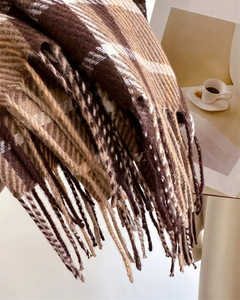 Close-up of thick plaid scarf in brown and beige with soft fringe and twill texture