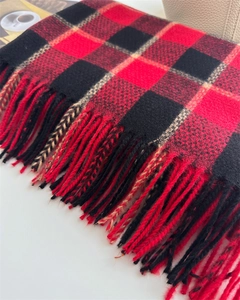 Gros plan sur une écharpe à carreaux rouge et noir imitation cachemire avec franges
