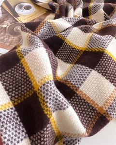 Gros plan d'une écharpe en cachemire épaisse à carreaux avec texture douce et franges