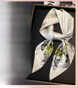 Detail of floral silk square scarves in green and orange prints with silky texture
