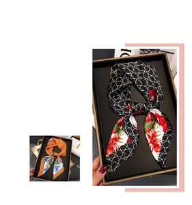 Detail of floral silk-feel scarves in black and orange patterns inside a gift box