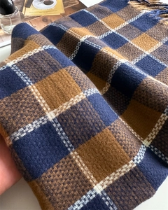 Gros plan d'une écharpe en cachemire à carreaux bleu et jaune avec pompons