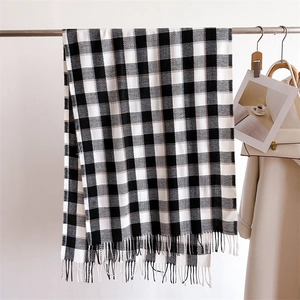 Gros plan d'une écharpe à carreaux noir et blanc avec franges en texture cachemire