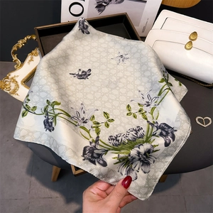 Detailed shot of silk scarf with grey floral pattern and green leaves in chic layout