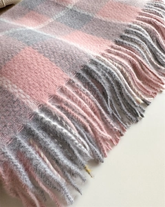 Gros plan de l'écharpe douce à carreaux avec des franges roses et grises pastel