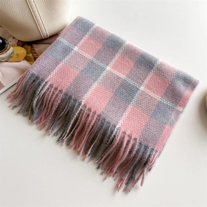Détail d'une écharpe à carreaux rose et gris avec de doux pompons sur fond blanc