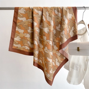 Detail of cloud pattern silk scarf draped on a rack with a white blazer and handbag