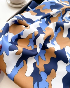 Detailed macro shot of blue and yellow cloud print silk scarf on a white ceramic plate