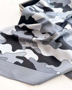 Macro detail of silk scarf showing grey camouflage pattern and smooth satin texture edges