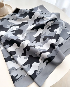 Detailed view of the gray camouflage pattern silk scarf with elegant satin finish on a table