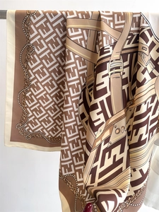 Detail view of silk scarf with vintage letter print and chain motifs on a metal hanger