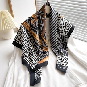 French vintage silk scarf with letter chain print draped over a shirt on a wooden hanger