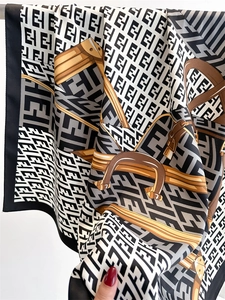 Macro detail of French vintage silk scarf showing geometric logo print and premium satin texture