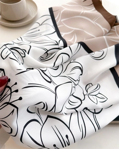 Detail of silk scarf showing vintage floral patterns and smooth satin texture on diagonal fold