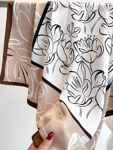 Close-up of vintage floral silk scarf featuring satin texture and hand-rolled brown edges