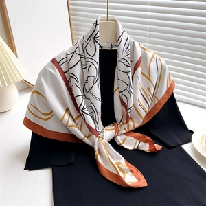 Close-up of a vintage floral silk scarf with amber borders styled on a black shirt