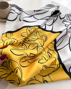Close-up of vintage floral silk scarf texture showing smooth yellow and white fabric
