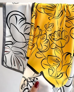 Detail of silk scarf showing yellow and white botanical floral print with smooth drape