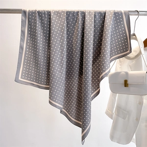Detailed view of the gray polka dot silk scarf draped on a metal bar with premium texture