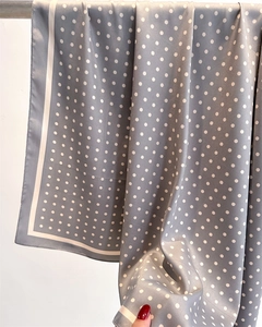 Detail of grey polka dot silk scarf featuring smooth texture and white border accents