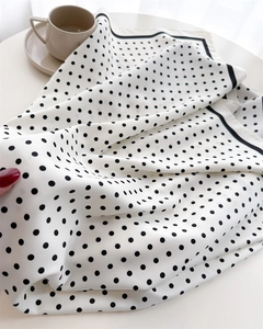 Detail of silk-feel scarf with black polka dots on white fabric and premium hem