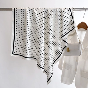 Close-up of a white polka dot silk scarf draped on a metal rack with a chic french style