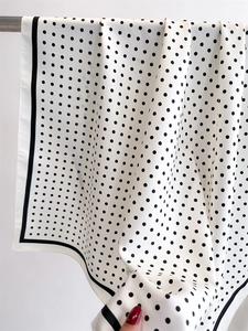Close-up showing the elegant drape and smooth texture of a polka dot silk scarf