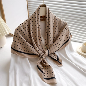 Polka dot silk scarf elegantly draped on a white shirt collar in soft morning light
