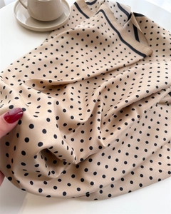 Detailed macro view of polka dot silk scarf texture with black hand-finished edges