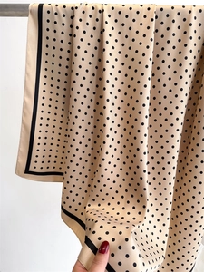 Detailed view of champagne polka dot silk scarf with elegant black rolled edge finish