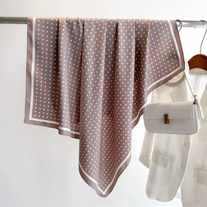 Close-up of elegant polka dot silk square scarf in dusty rose draped on a metal hanger