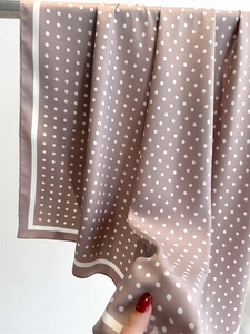 Close-up of vintage pink polka dot silk scarf with satin finish and smooth texture
