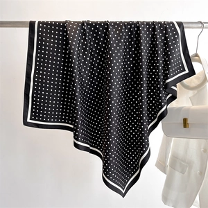 Close-up of black silk scarf with white polka dots and stripe border on a metal rod