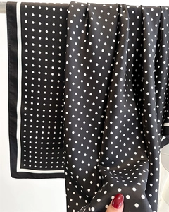 Detail view of black satin scarf with white polka dots showing smooth fabric texture