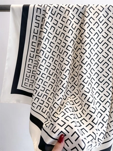 Detailweergave van de zijdeachtige textuur en geometrisch patroon van een zwart-witte sjaal
