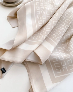 Detail van zijden sjaal met beige geometrische patronen en gestikte rolzomen